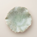 Round ceramic wall art with textured surface on a light beige background