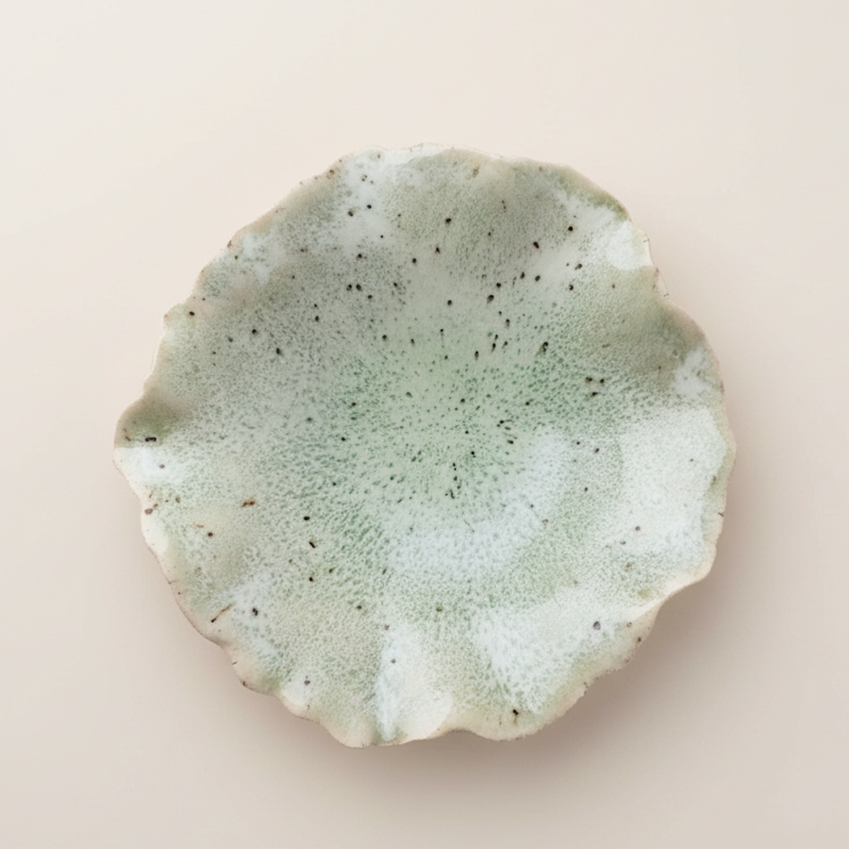 Round ceramic wall art with textured surface on a light beige background