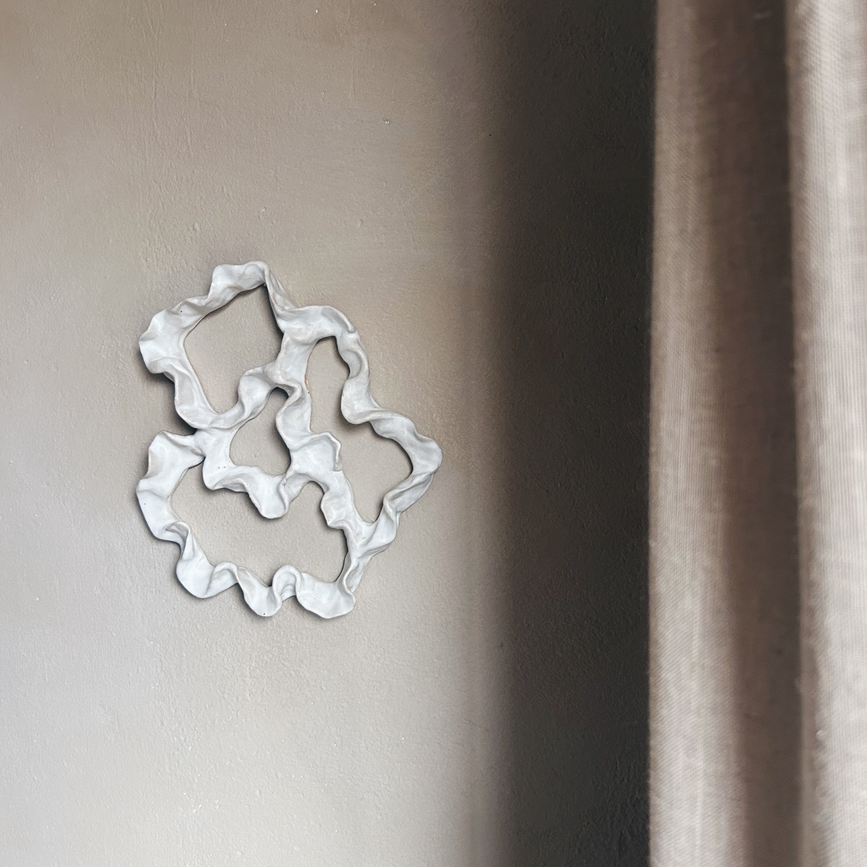 Decorative ceramic wall art with wavy edges on a wall