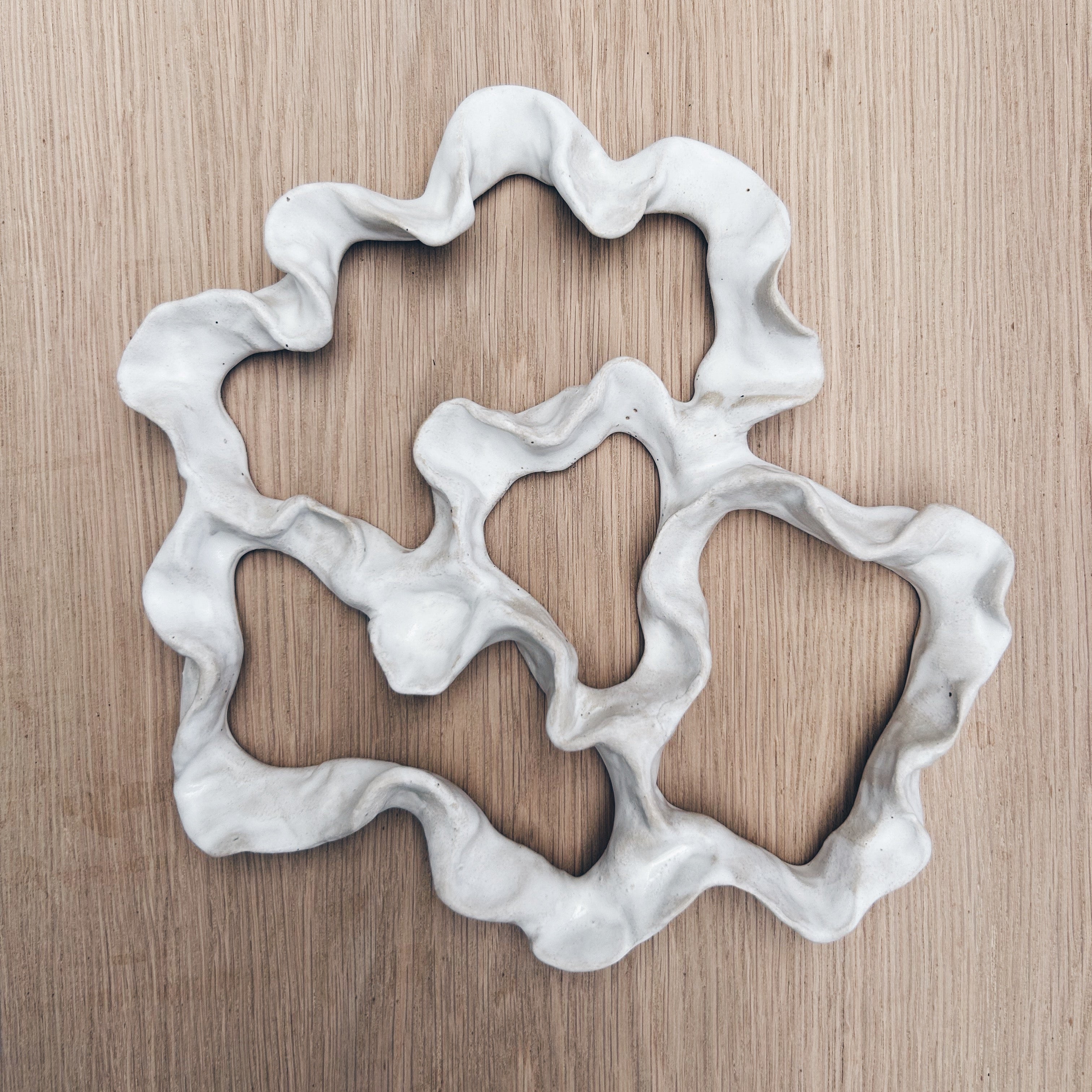 Decorative ceramic wall art with wavy edges on a wooden surface